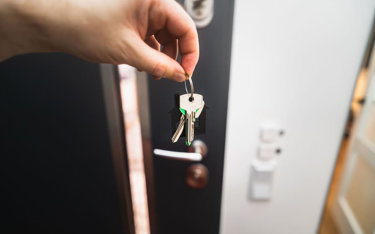 House keys held near an open residential doorway
