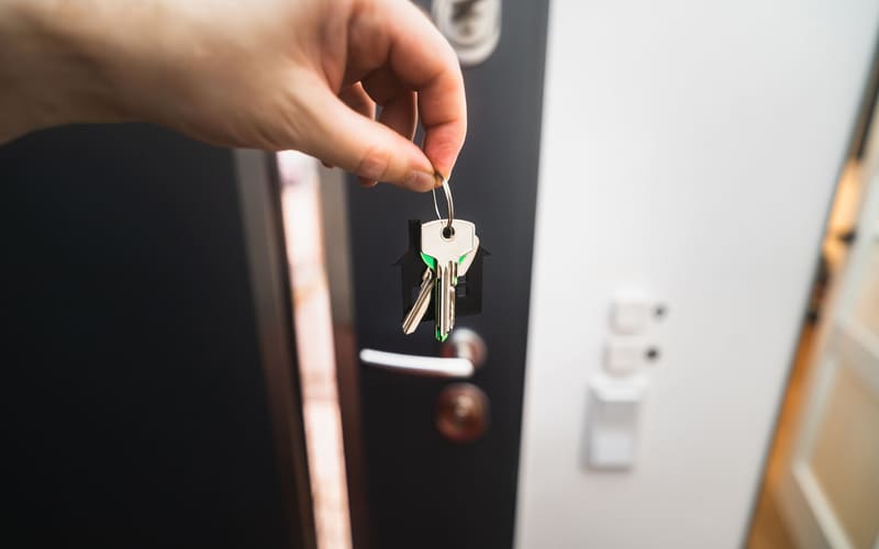 Representative stock photo of house keys held near an open residential doorway